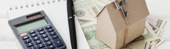 Model of cardboard house with key, calculator, notebook, pen and cash dollars. House building, loan and real estate. Cost of public utilities, insurance, rent or buying a new home concept. mortgage