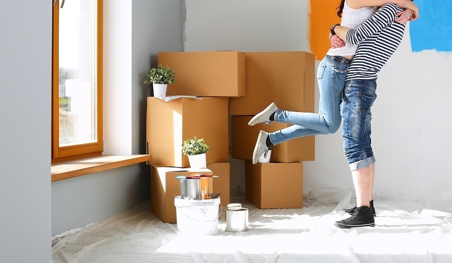 young couple hugging in room full of boxes after moving into their dream home after applying for a mortgage