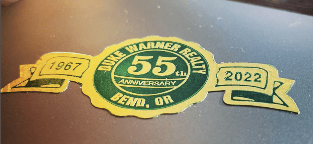 green and yellow sticker that says duke Warner realty 55th anniversary bend, or