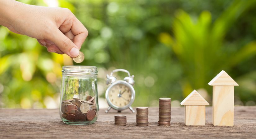 Hand's women putting golden coins in money jar. Concept of real estate investments Home insurance Savings plans for housingTime to save The concept of financial savings to buy a house.