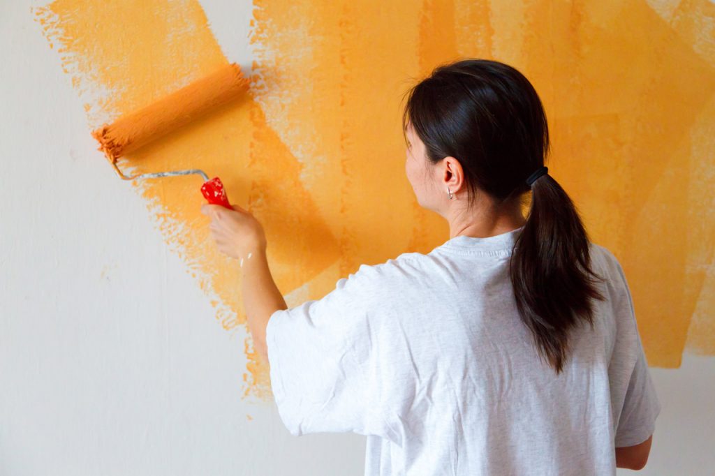 woman painting a wall yellow, lower home value