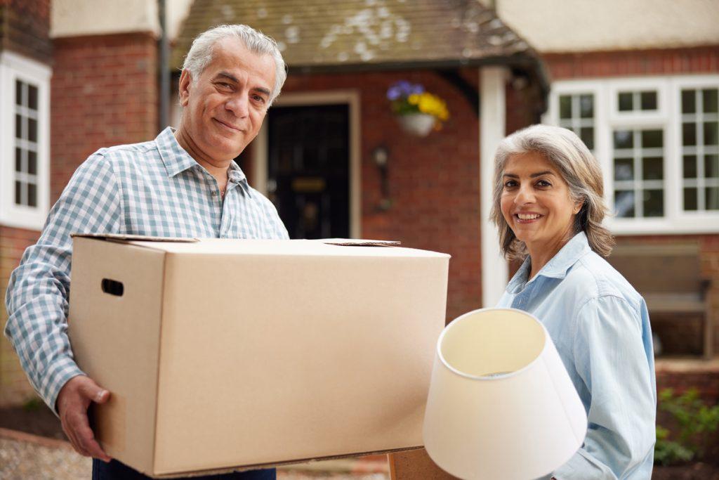 couple carrying boxes into newly purchased dream home should you buy new or used home