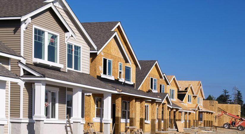 Perspective photo of a row of similar style houses during various phases of construction. should you buy a new or used home