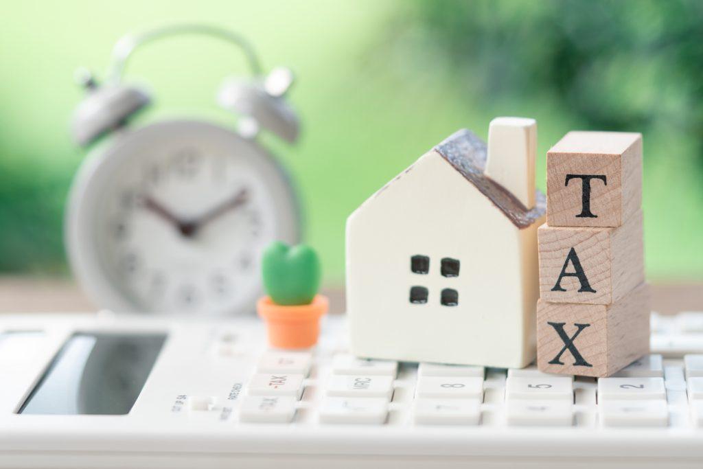 A model house model is placed on wood word TAX . concept: bend property taxes tax